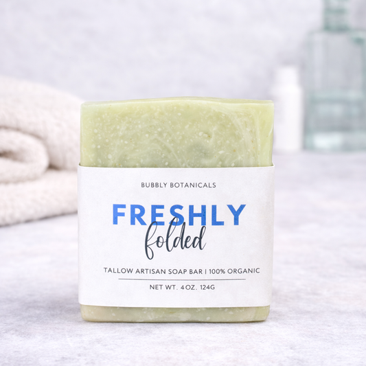 Bar of freshly folded grass-fed tallow soap with a label on a neutral background