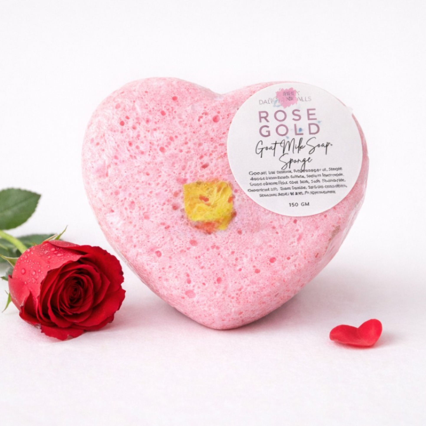 Heart-shaped pink bath soap with a rose gold label next to a red rose on a white background