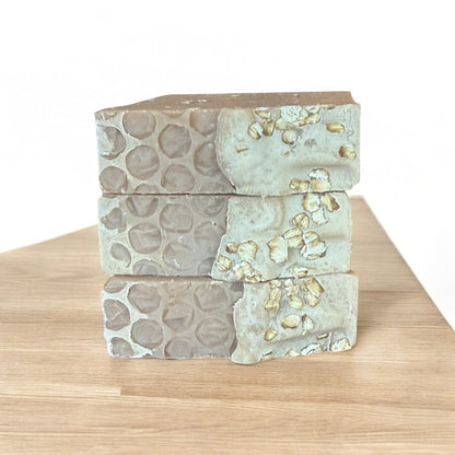 Three Sweet Honey & Oats tallow soaps by Bubbly Botanicals stacked on a wooden surface