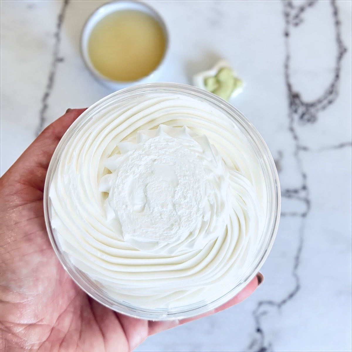 Hand holding a jar of tallow body butter by Bubbly Botanicals